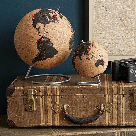 Cork globe with push pins on a suitcase.