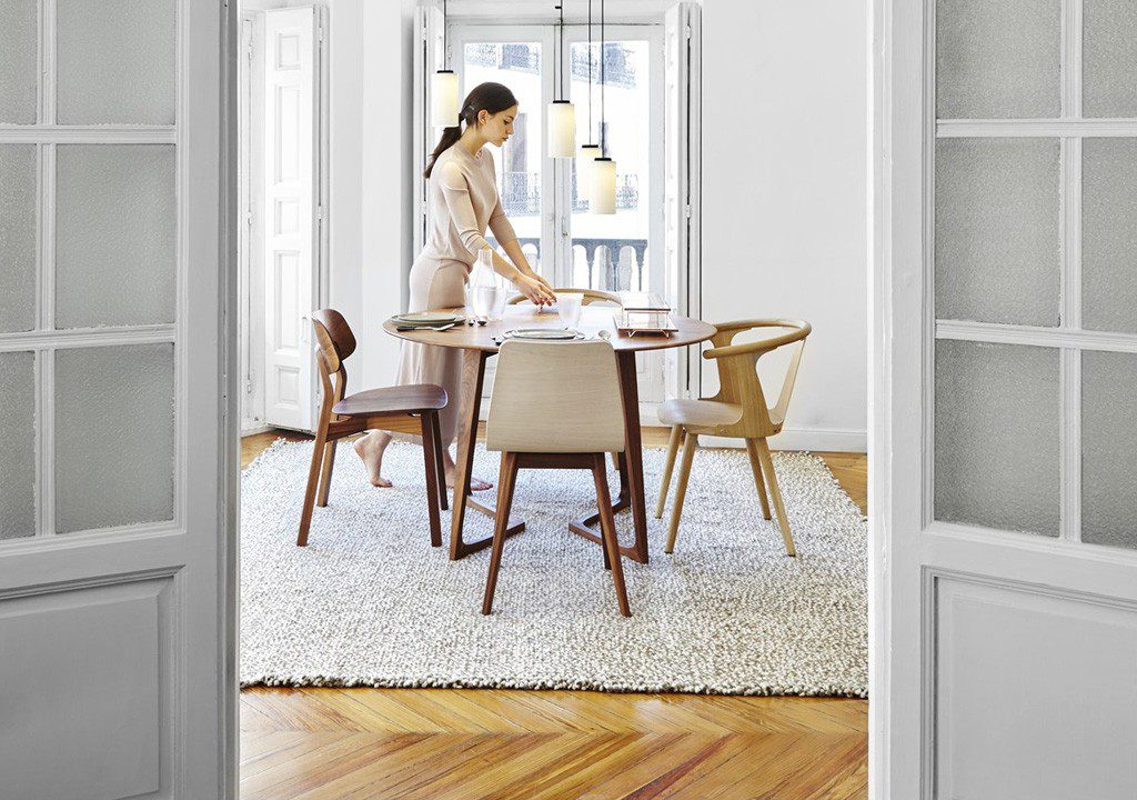 Woman setting table in modern dining room.