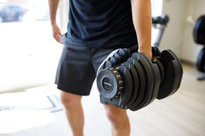 Man lifting adjustable Vortex dumbbell.