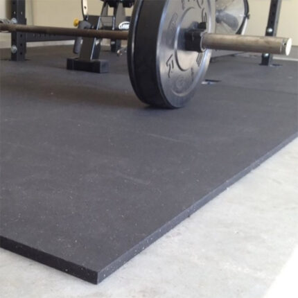 Black rubber gym floor mat with weights.