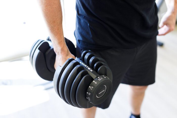 Person lifting a black adjustable dumbbell.