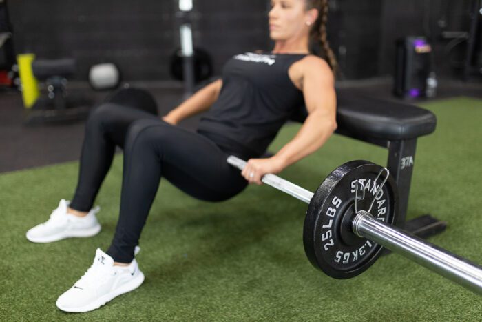 Woman doing a hip thrust with a barbell.