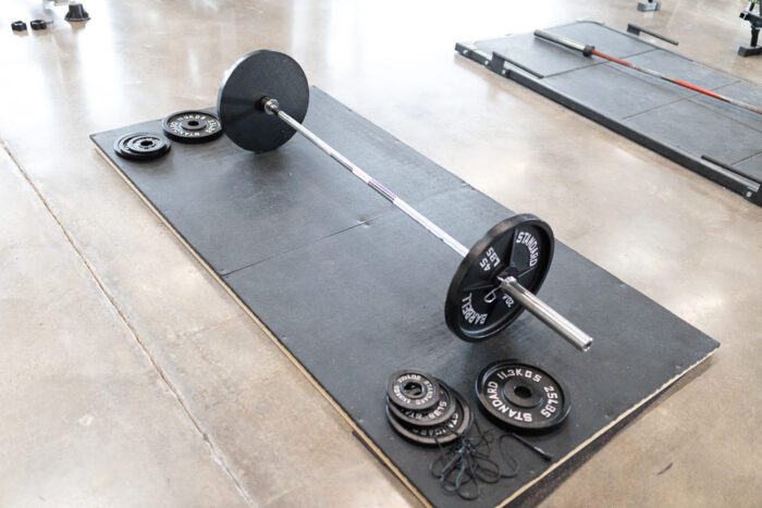 Weightlifting barbell with plates on mat.