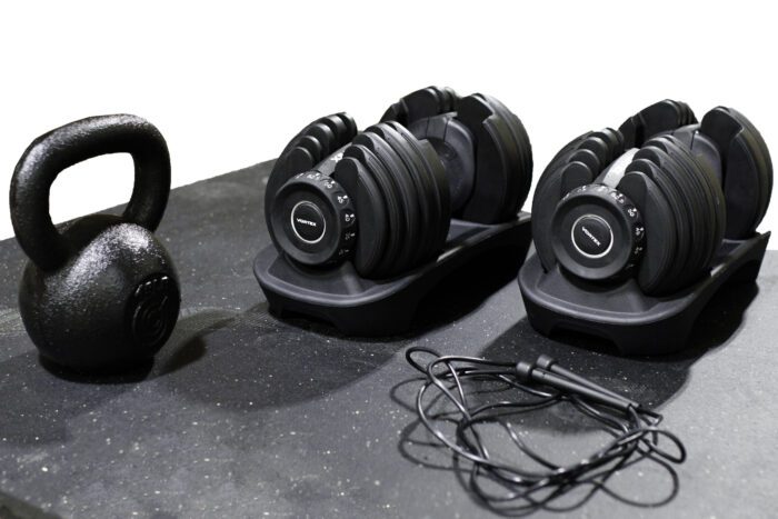 Black adjustable dumbbells, kettlebell, and jump rope.