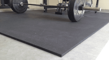 Black rubber gym mat with barbell.