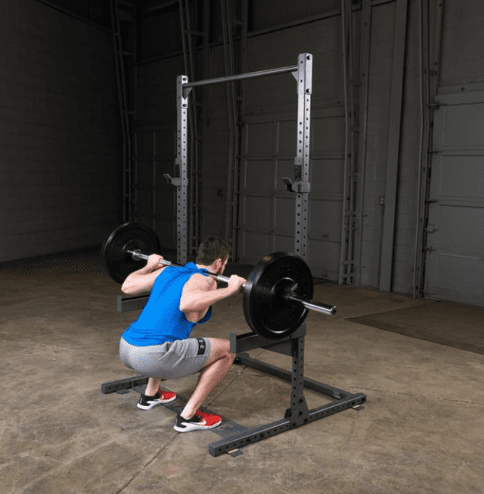 Man doing squats with barbell in gym.