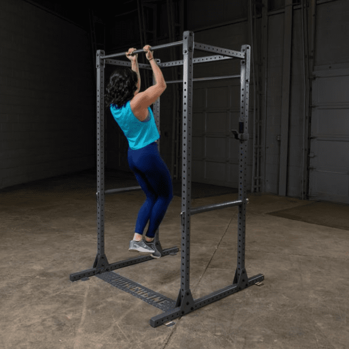 Woman doing pull-ups on a squat rack.