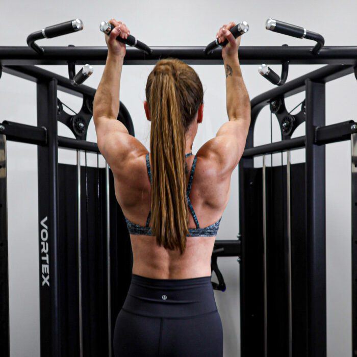 Woman doing pull-ups in a gym.