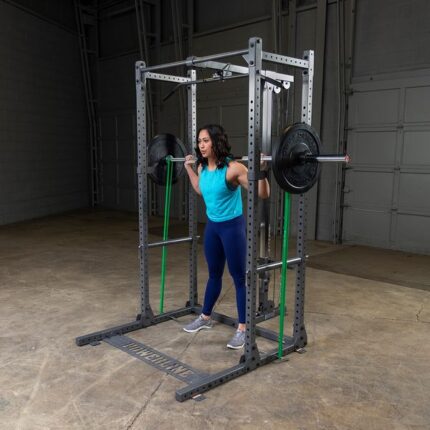 Woman squatting with barbell in a gym rack.