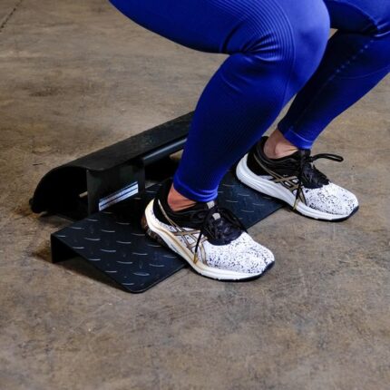 Person in blue pants using a squat wedge.