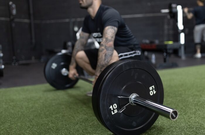 Man lifting 10 lb weight plate in gym.