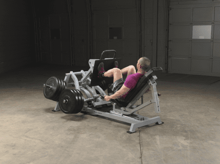 Man using leg press machine in gym.