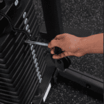 Hand adjusting weight stack on gym machine.