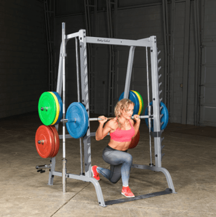 Woman doing a lunge in a weight cage.