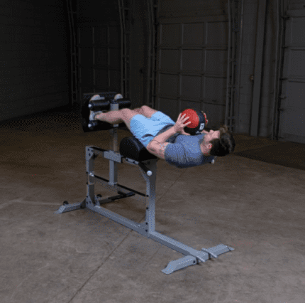 Man using a hyperextension bench with a ball.