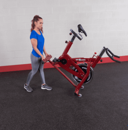 Woman pushing red exercise bike.