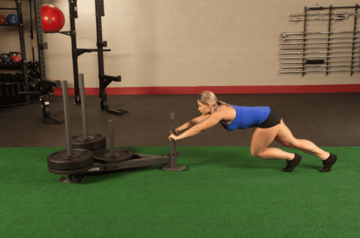 Woman doing a weighted sled push.