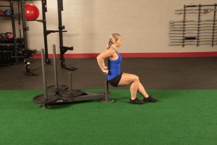 Woman doing a dip exercise on a sled.