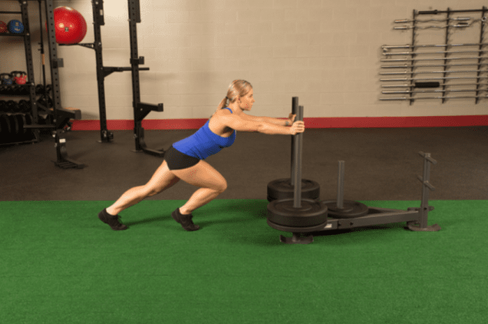 Woman pushing a weighted sled at gym.