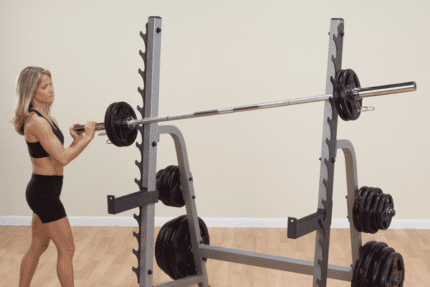 Woman lifting weights in a squat rack.