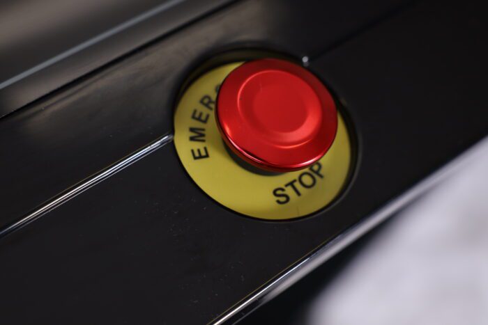 Red emergency stop button on black panel.