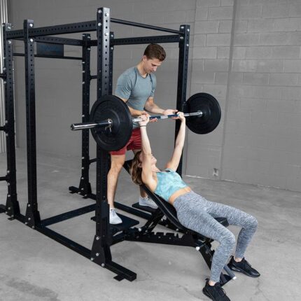 Man spotting woman bench pressing in a gym.