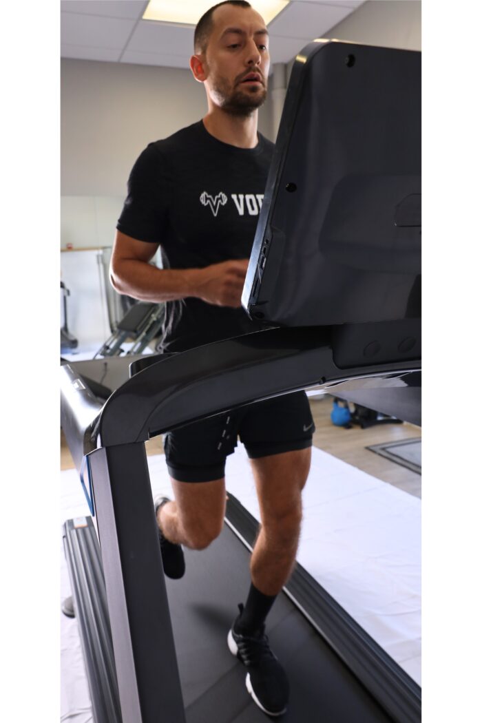 Man running on a treadmill in a gym.