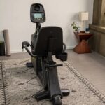 Black recumbent exercise bike in room.