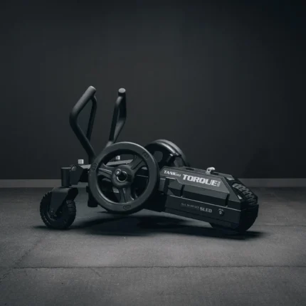 Black fitness sled on dark floor.