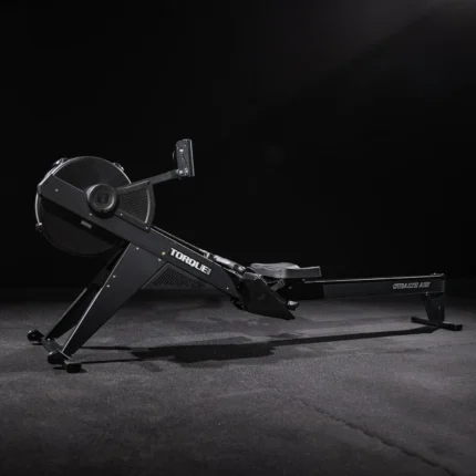Black rowing machine in dark room.
