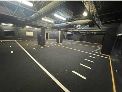 Dark indoor space with marked floors, ceiling lights.