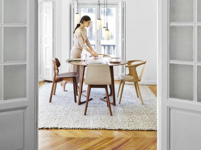 Woman setting table in modern dining room.